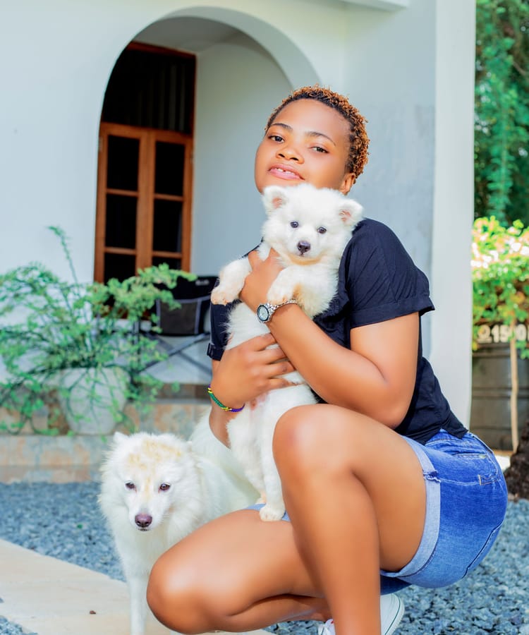 A woman holding her two white dogs in a doorway