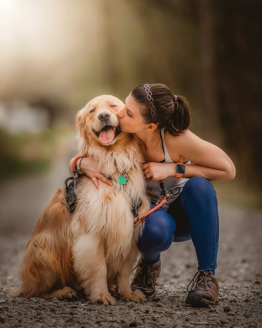 Woman holding her golden retriever close at golden hour